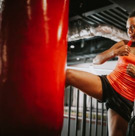 Beautiful black fit woman in sportswear boxing kicking bag in the gym.