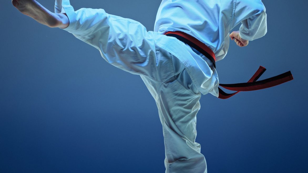 Young boy training karate on blue studio background