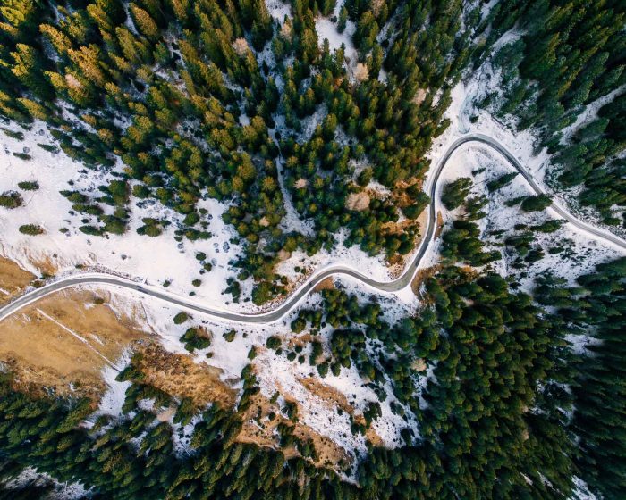 aerial-view-of-snowy-forest-with-a-road-captured-f-PAUZRF7