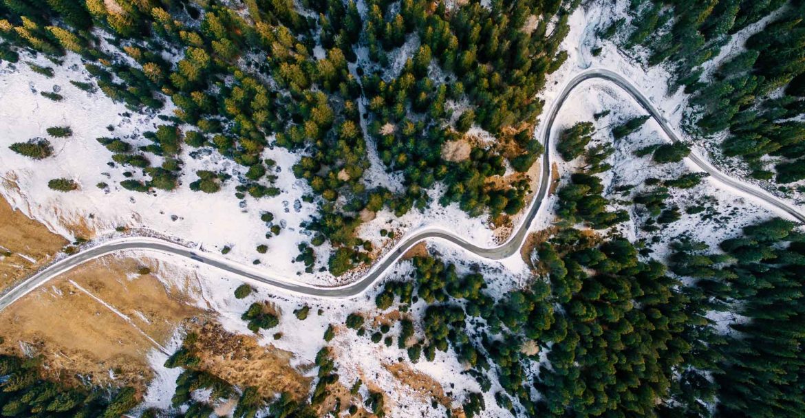 aerial-view-of-snowy-forest-with-a-road-captured-f-PAUZRF7