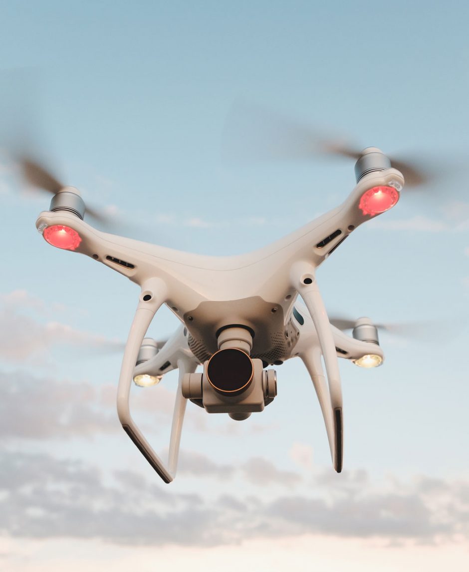 white-drone-hovering-in-a-bright-blue-sky-PMFRLG7
