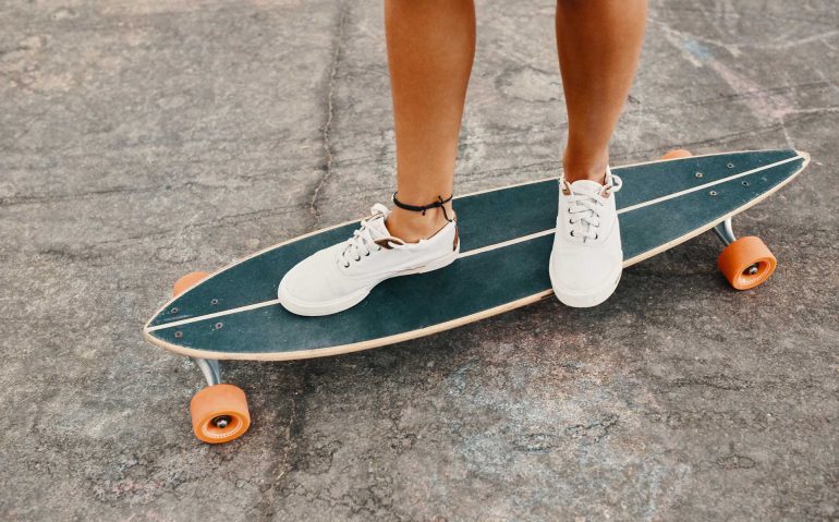 woman-in-sneakers-riding-skateboard-outdoor-on-asp-KXD8CUS