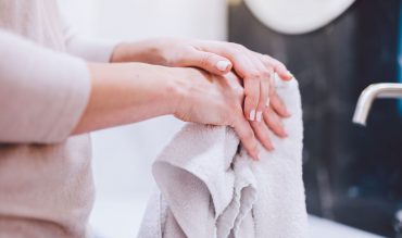 woman-wiping-hands-in-towel-after-washing-them-hyg-22ZGBH4